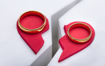 Wedding rings positioned on either side of a broken heart