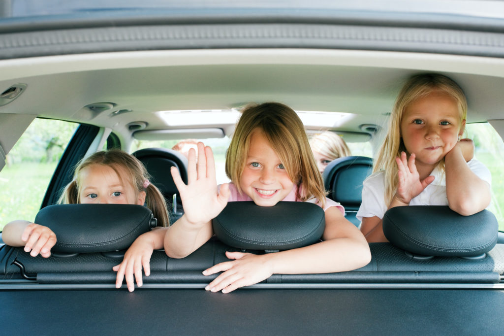 Photo of 3 children in back seat of a vehicle